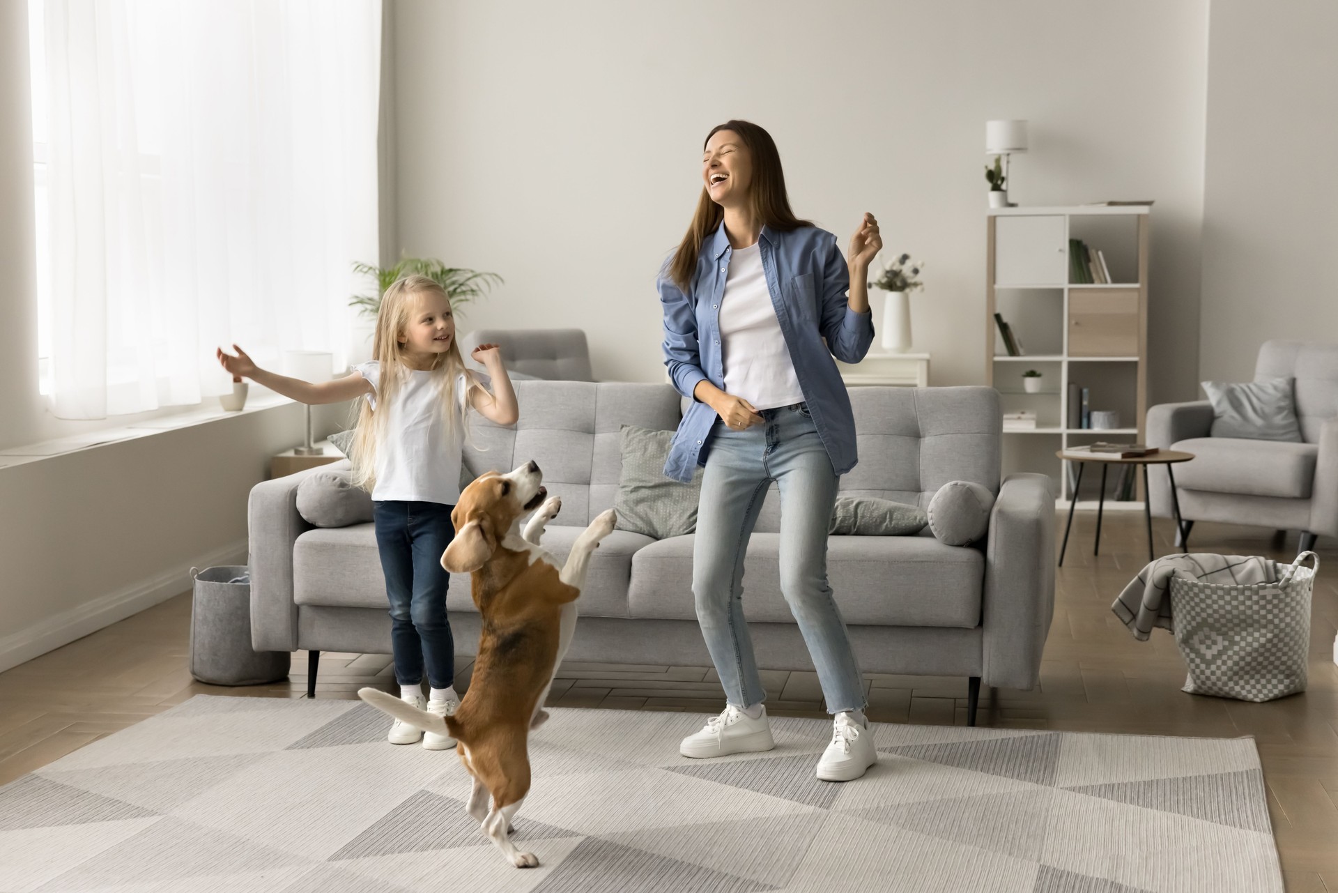 Excited mom and happy daughter kid dancing with pet