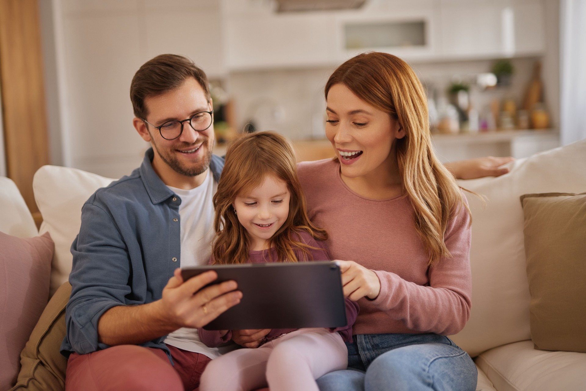 Curious little girl using the tablet with her parents in the living room